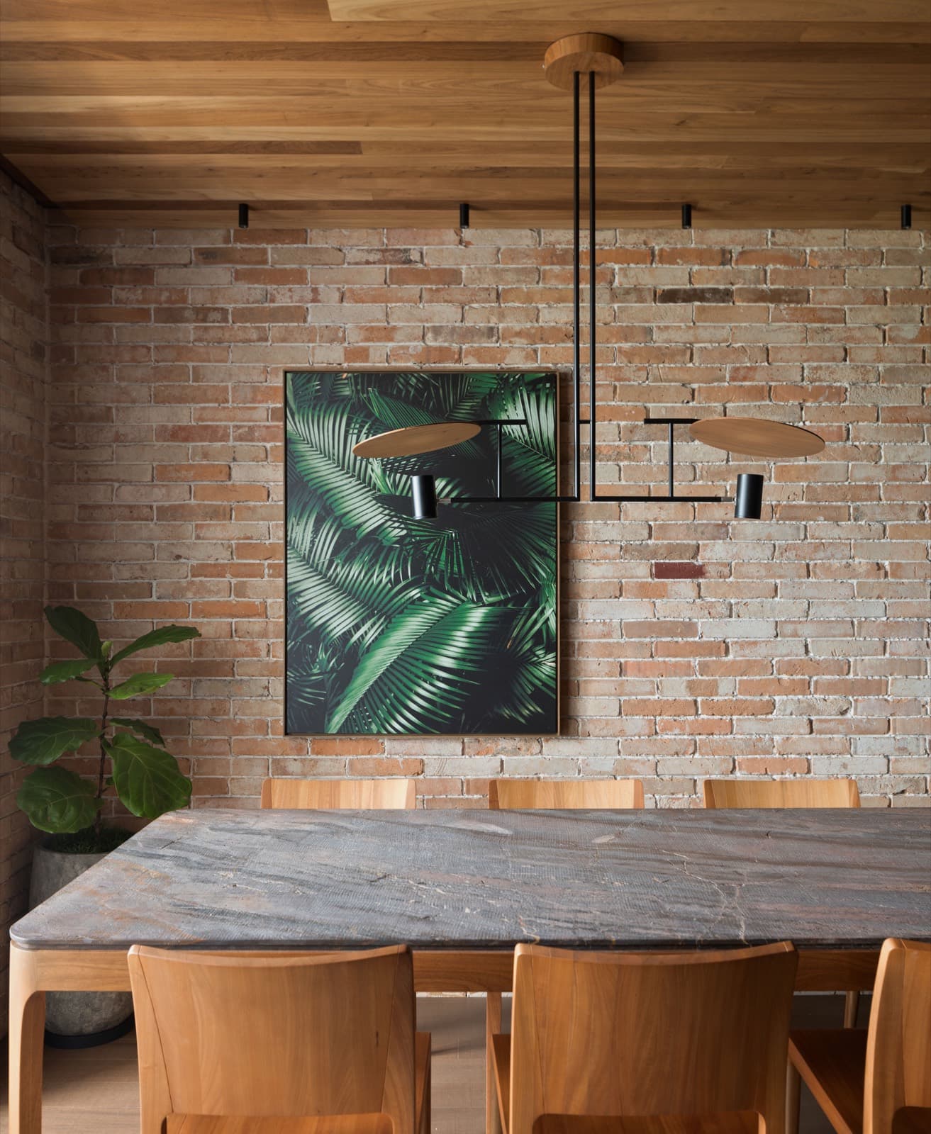 Sala de jantar com mesa em pedra e pendente linear