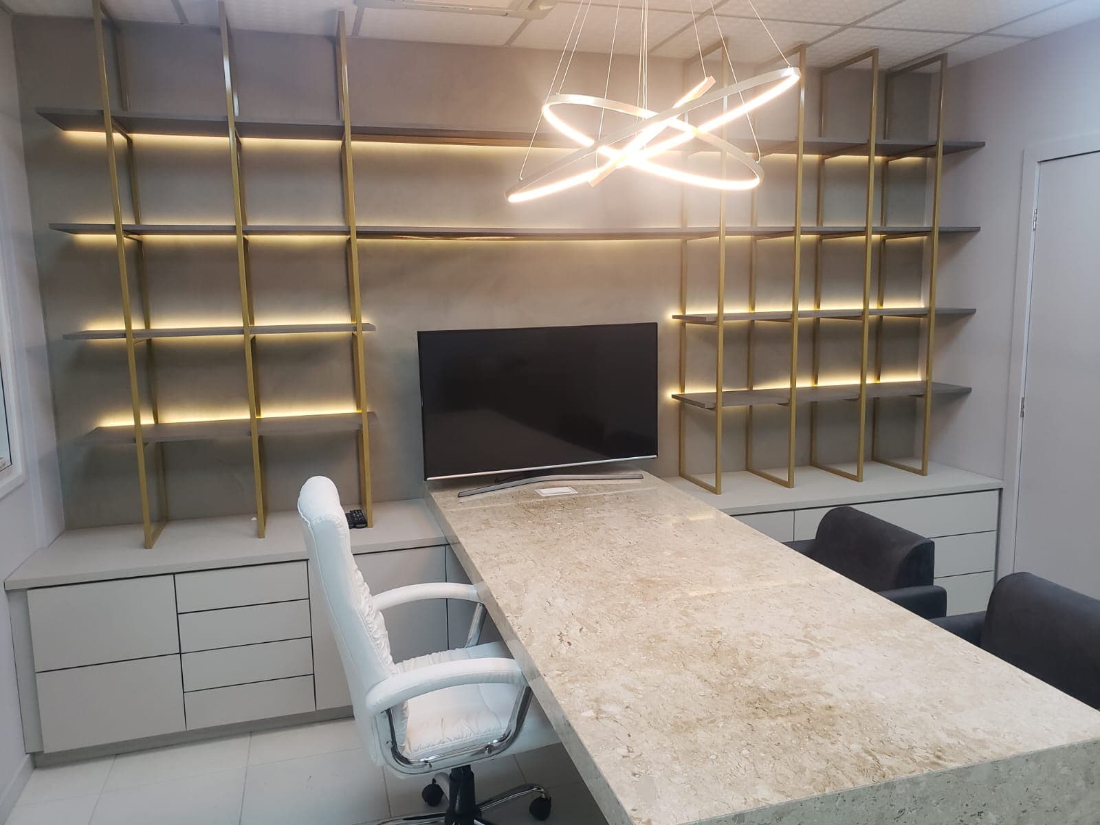 Sala de reunião com estantes douradas e mesa de mármore
