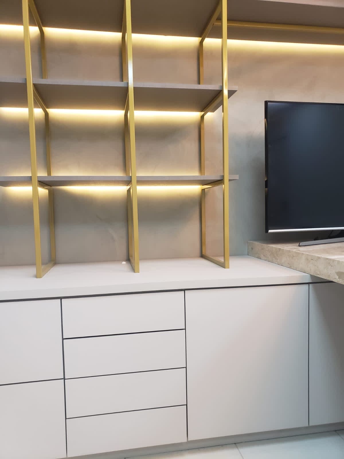 Estante dourada com painel de TV integrado