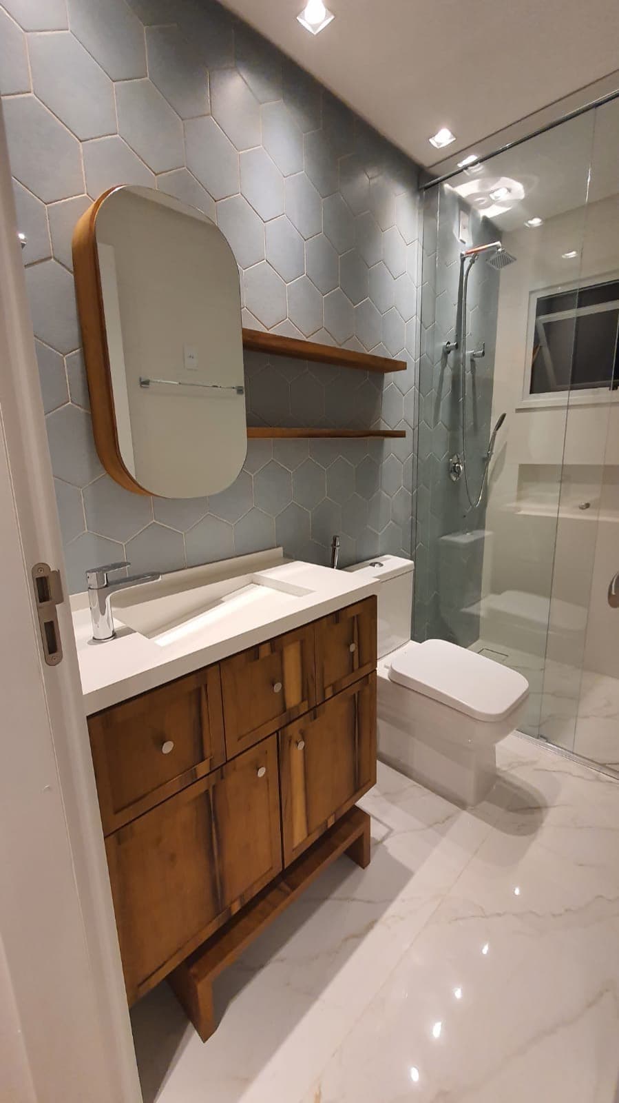 Banheiro com revestimento hexagonal e gabinete de madeira