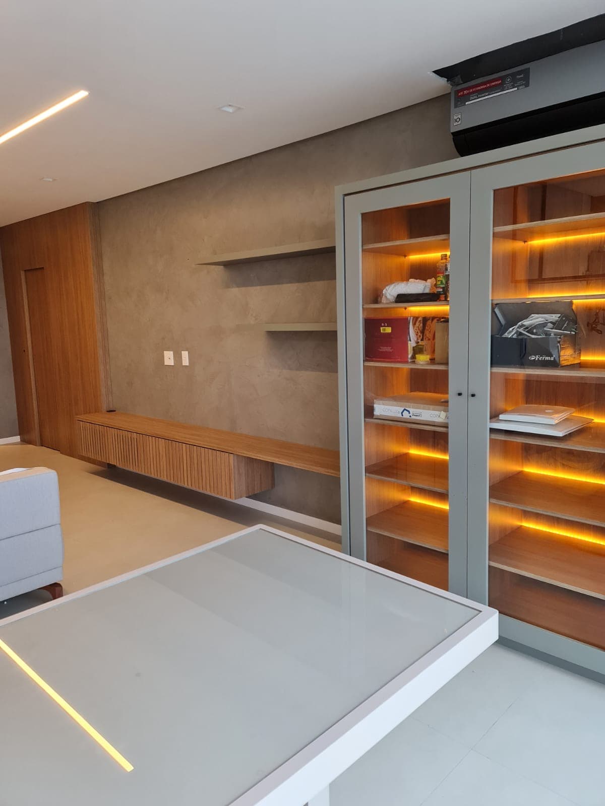 Home office com estante de vidro iluminada e bancada ripada
