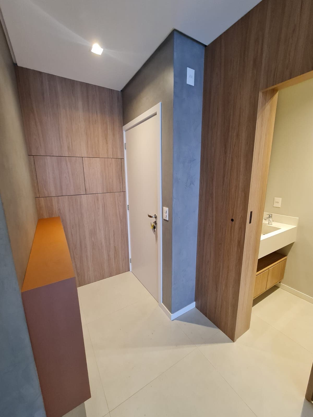 Hall de entrada com aparador laranja e marcenaria amadeirada