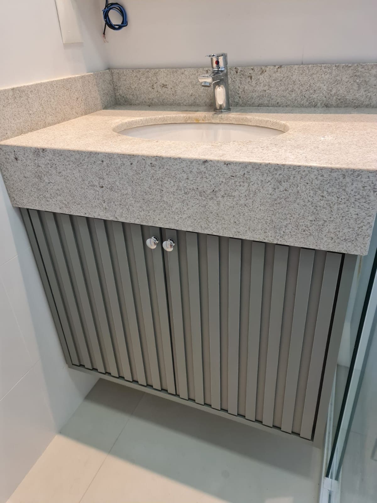 Lavabo com gabinete ripado e bancada de granito